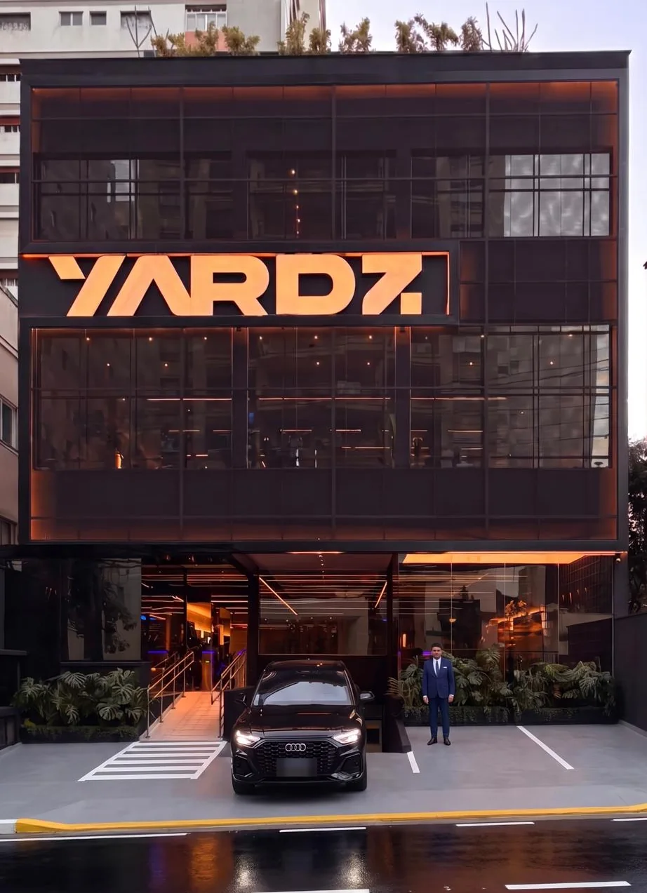 Fachada da YARDZ House, um prédio de quatro andares com o letreiro iluminado