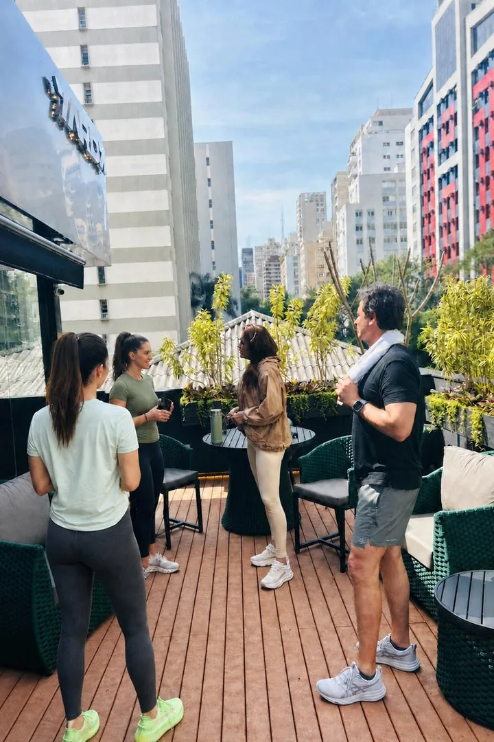 Alunos conversando no rooftop da YARDZ, com vista para os prédios dos Jardins